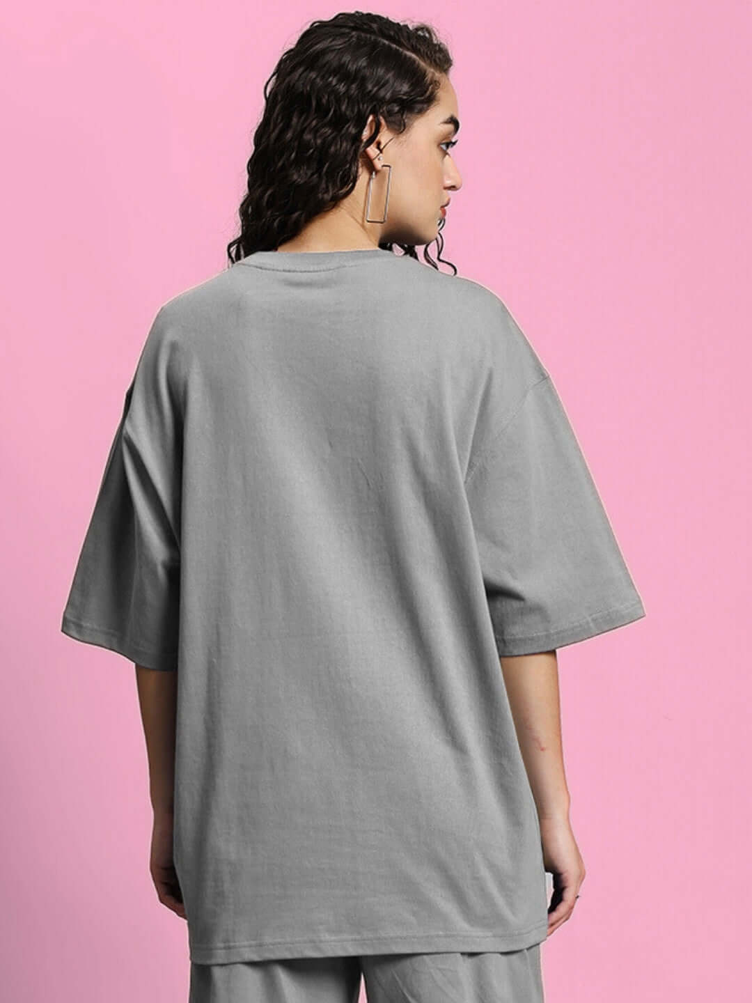 Back view of a woman wearing a grey oversized T-shirt made from premium cotton fabric, styled with loose fit sleeves.