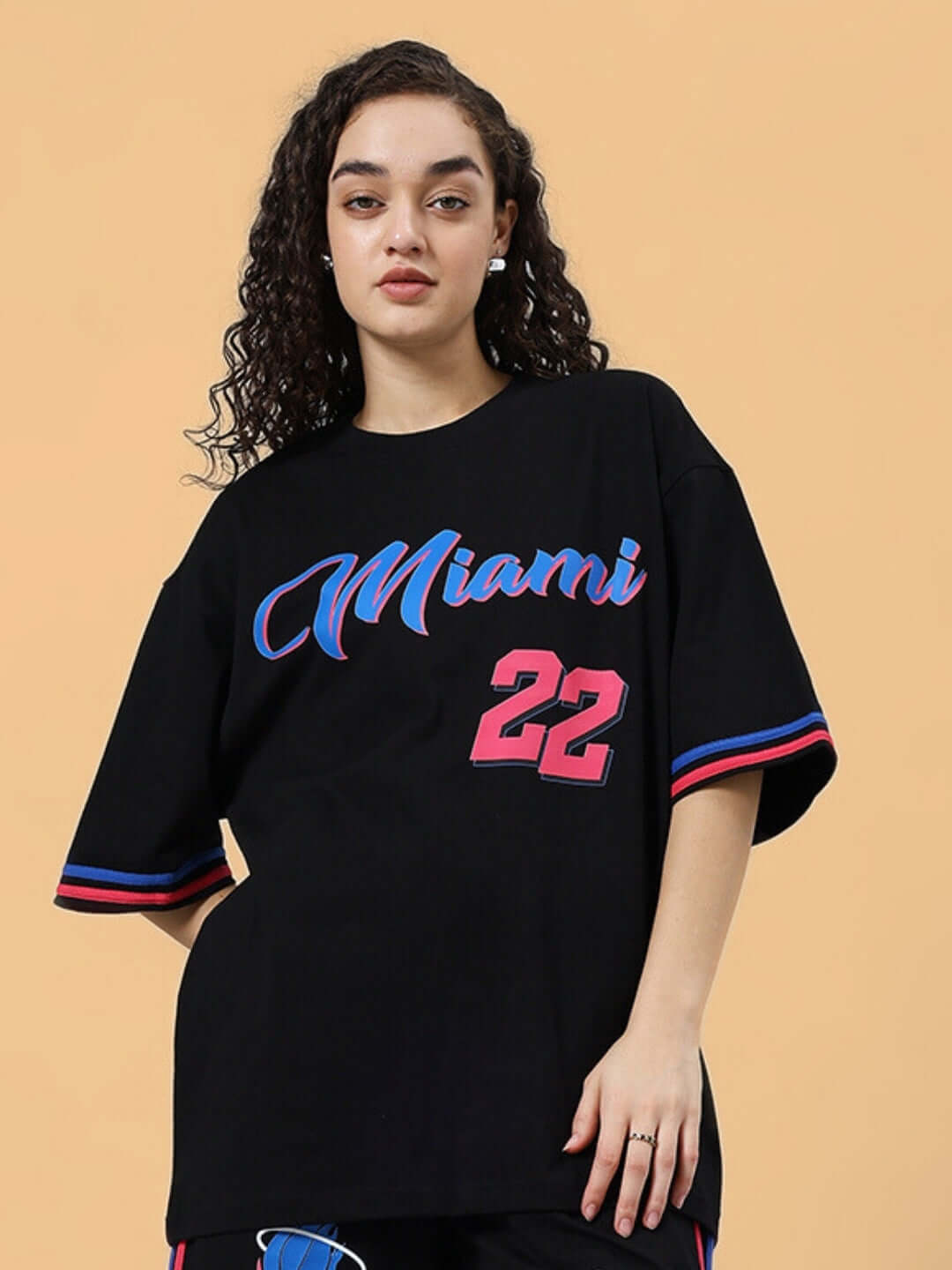 Woman wearing black over-sized Miami t-shirt, featuring premium cotton blend, styled for casual comfort. Made in India.