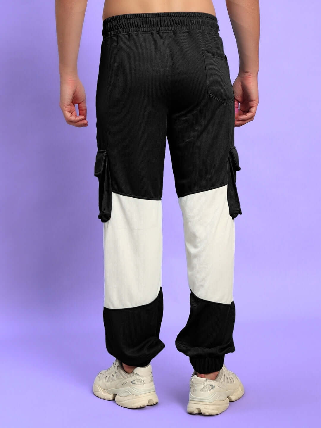Rear view of Radiant Relaxed Fit Joggers in black and white, worn by model on purple background, showcasing cargo pocket design.