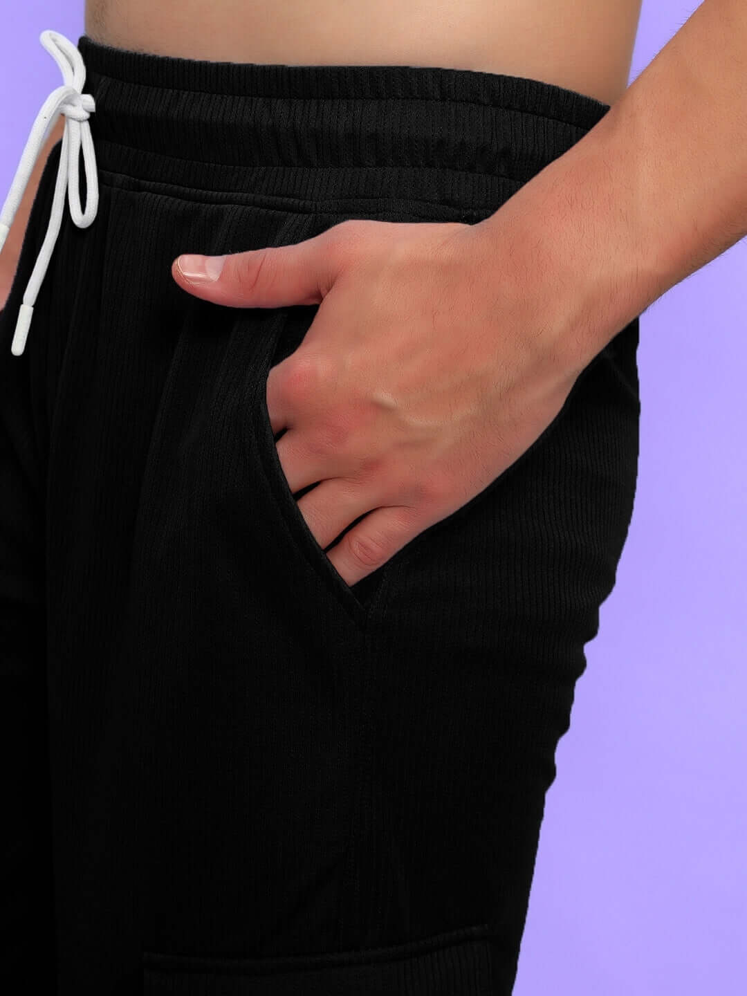 Close-up of a hand in the pocket of Radiant Relaxed Fit Joggers, black with white drawstring, showcasing textured fabric and stitch detailing.