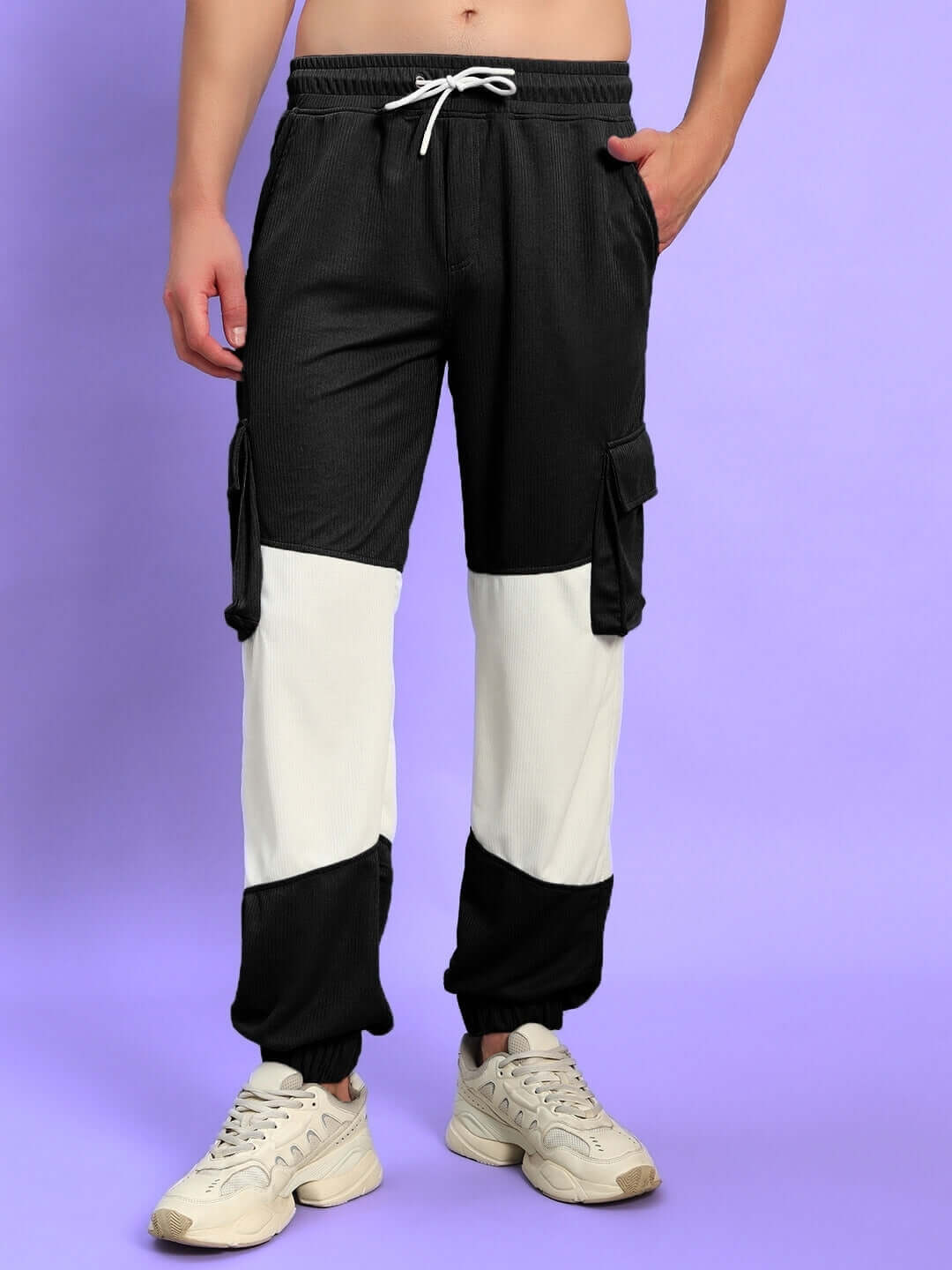 Model wearing black and white relaxed fit joggers with pockets, showcasing casual style on a light purple background.