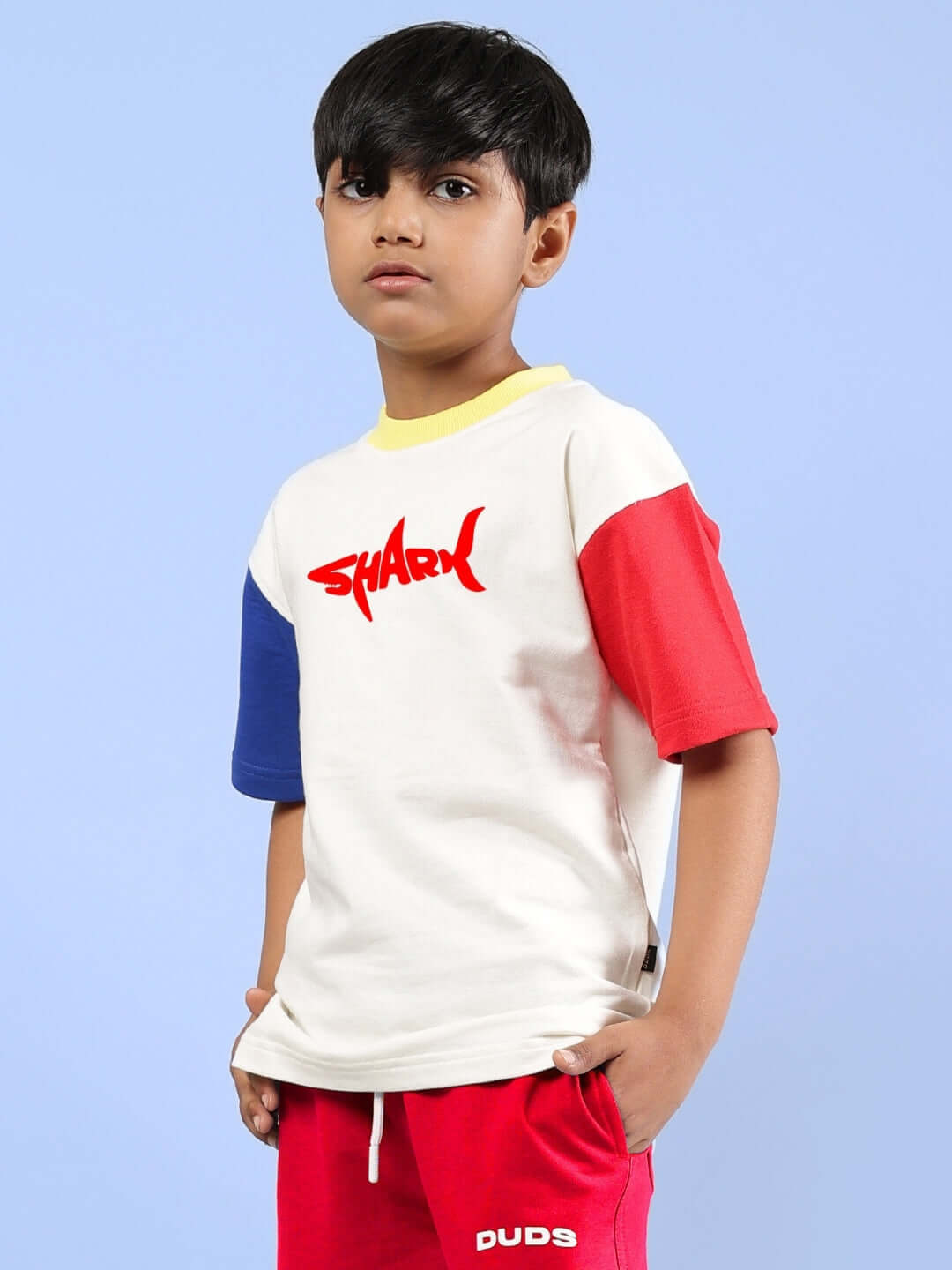 Boy wearing off-white shark fish printed oversized t-shirt with red and blue sleeves by DUDS.