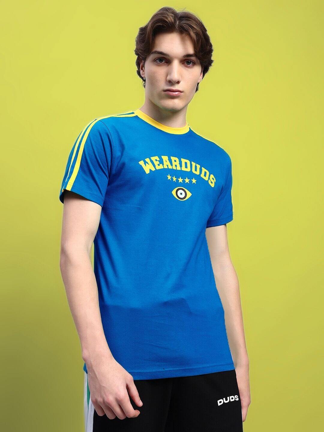Man wearing a blue Irish regular fit t-shirt with text and eye design, made of premium heavy gauge cotton, styled in front of a green background.