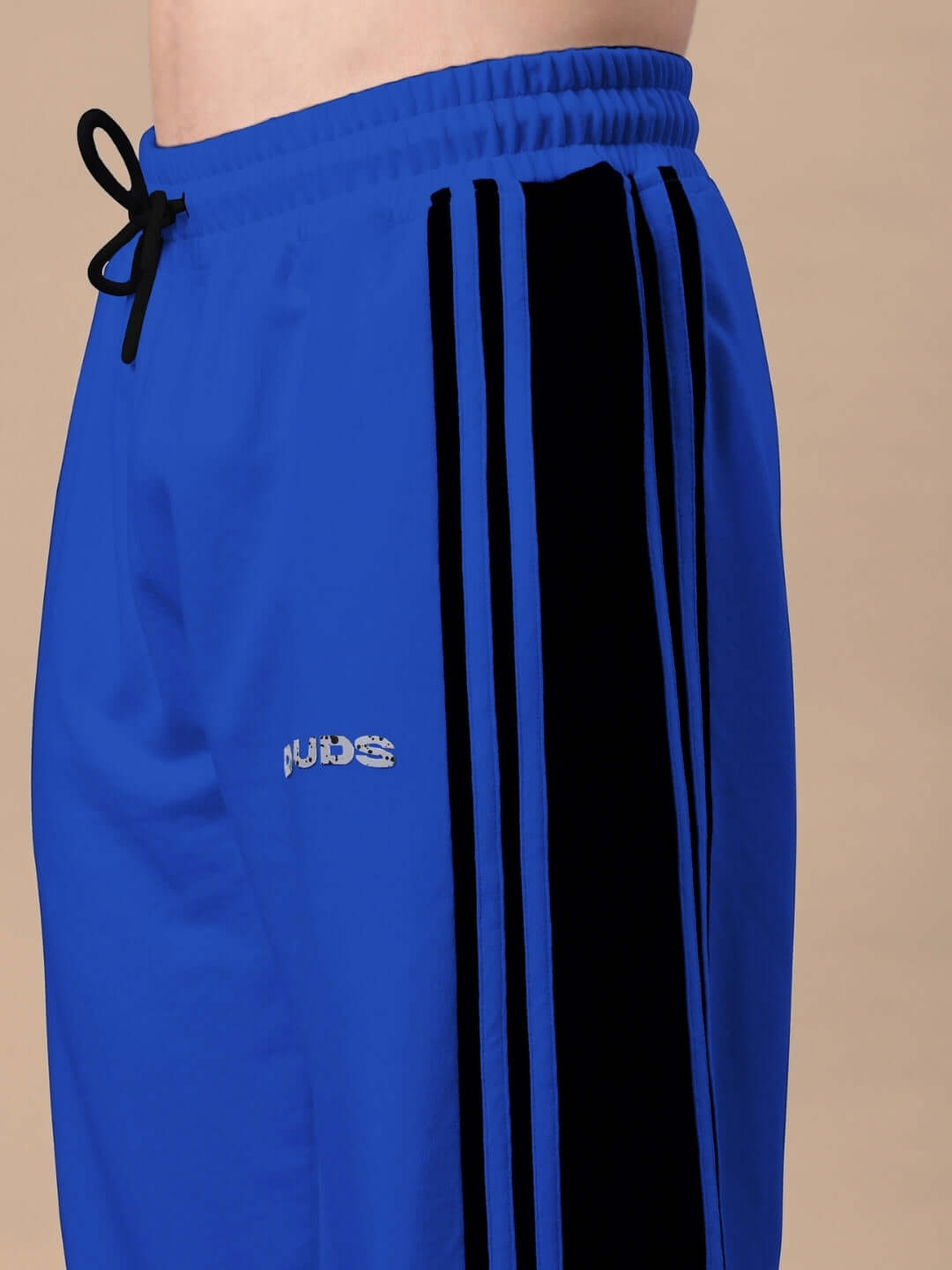 Close-up of blue and black contrast joggers with side stripes by DUDS, featuring elastic waistband and drawstring.