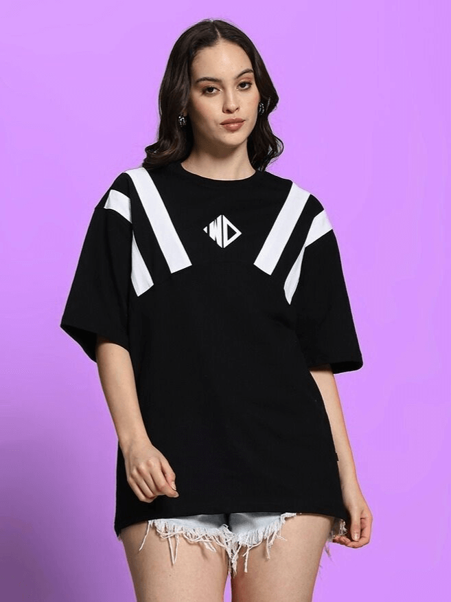 Woman wearing black oversized T-shirt with white stripes and logo, styled with denim shorts; perfect for casual wear.