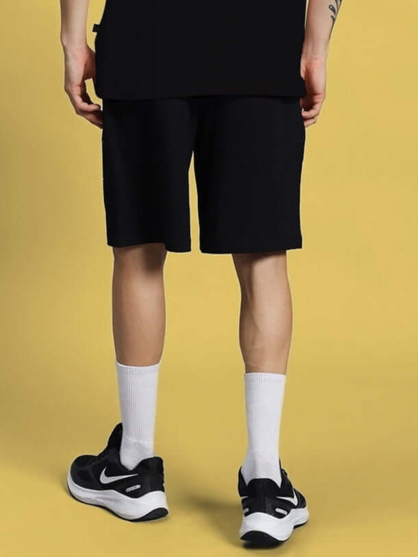 Back view of Funny Chicken Summer Shorts in black, showcasing knee-length design, paired with white socks and black sneakers.