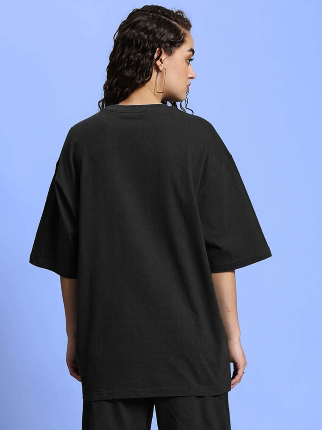Woman wearing black oversized t-shirt made from premium cotton and elastane, showcasing a relaxed fit. Perfect casual wear option.