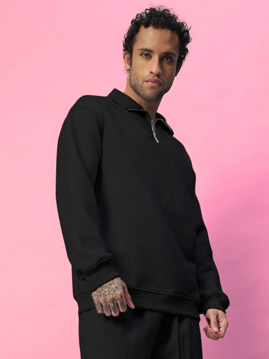 Model wearing BONA-FIDE Fleece Sweatshirt in black against pink background, showcasing casual fit and style.