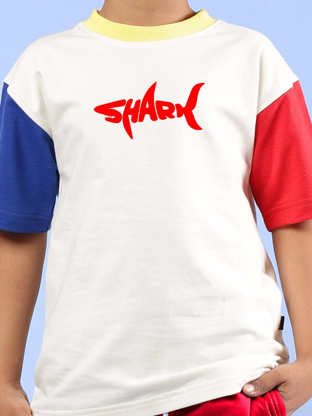 Off-white oversized t-shirt with shark print for kids, featuring colorful sleeves.