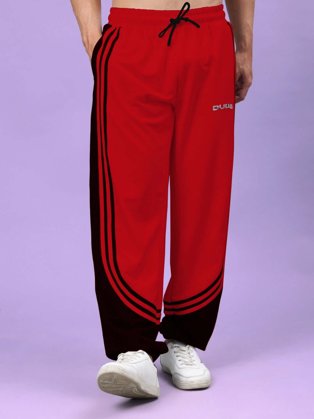 Red and black contrast joggers by DUDS, featuring a modern curve design, worn with white sneakers.
