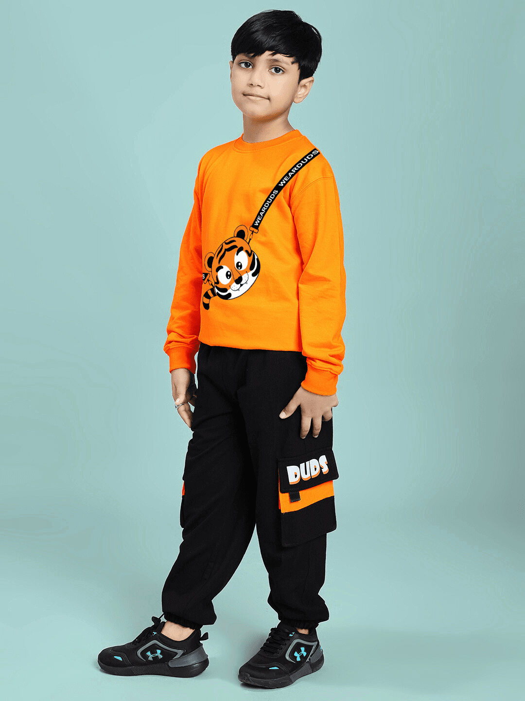Child wearing TIGON KIDS CO-ORD SET FOR BOYS AND GIRLS ORANGE BLACK, featuring a vibrant orange top and sleek black pants