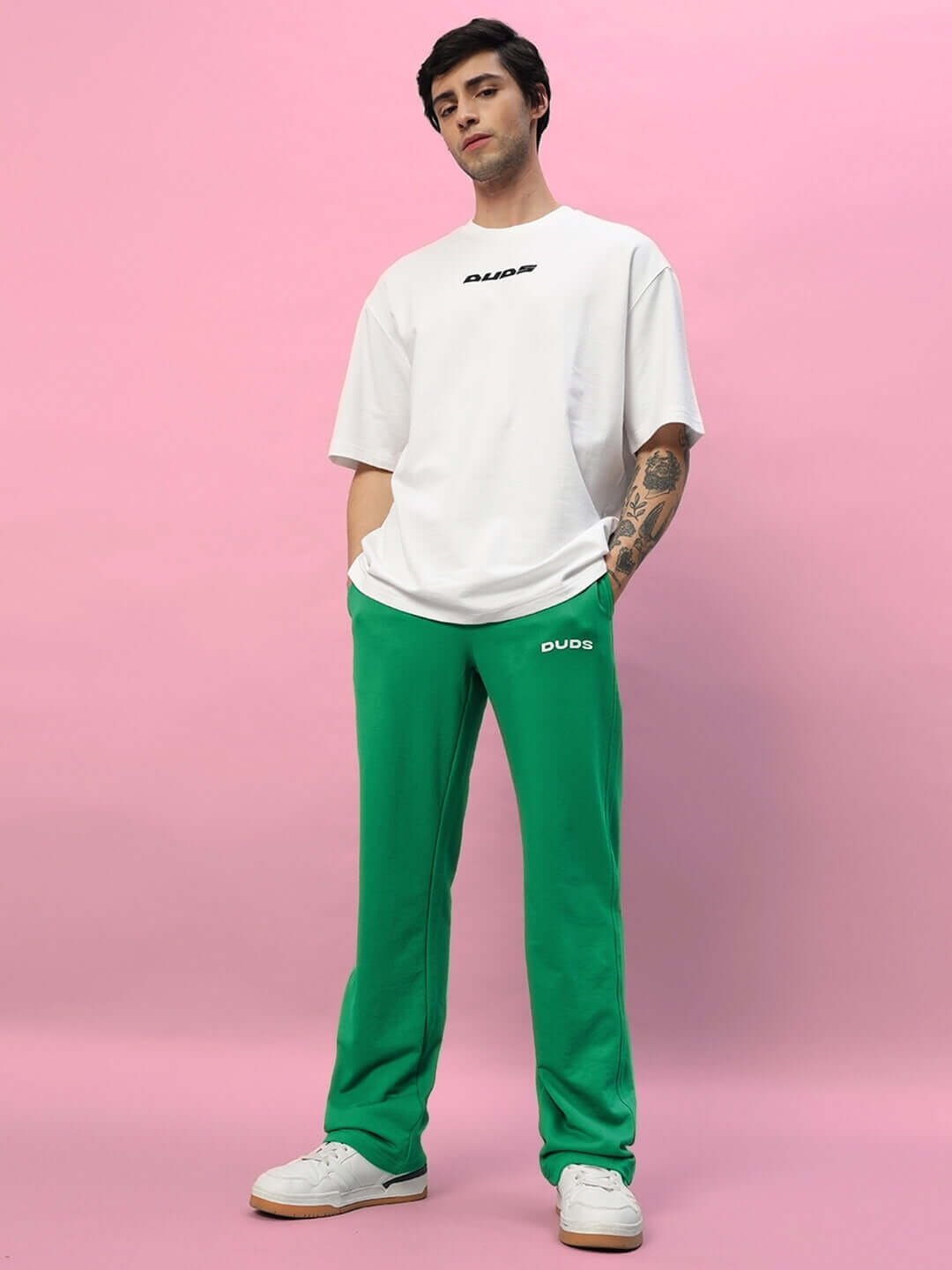 Model wearing green NEW ERA Relaxed Fit Joggers by DUDS with white t-shirt, showcasing casual fashion style.