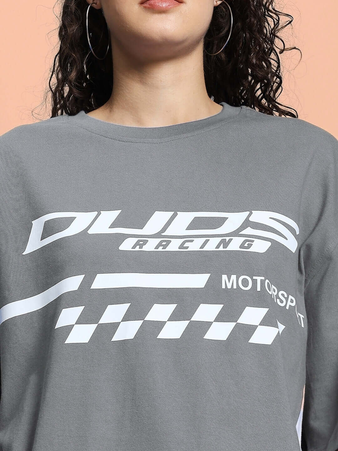 Grey oversized women's t-shirt featuring racing-themed graphics, made with premium cotton blend, styled with hoop earrings.