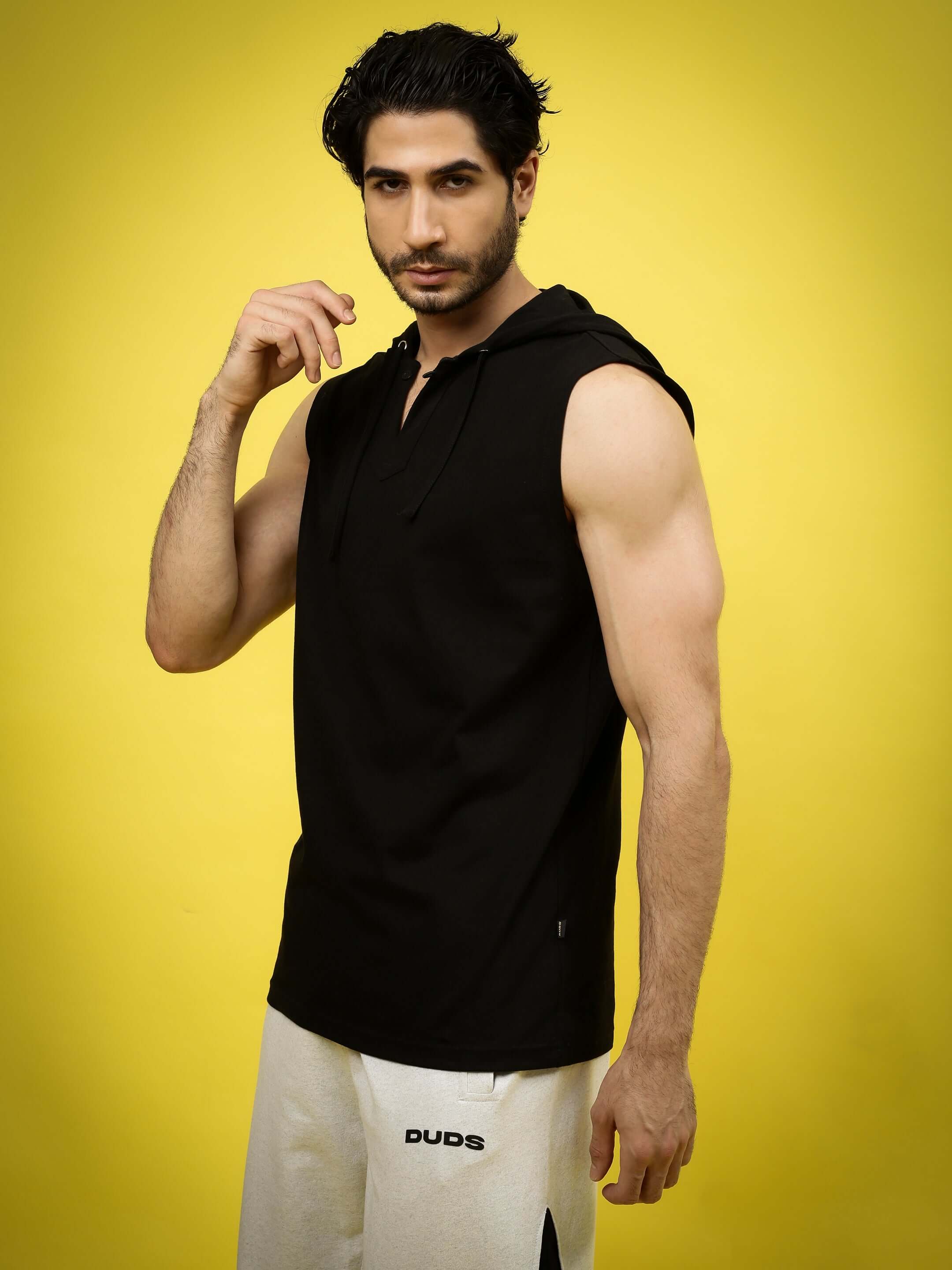 Model wearing ACME OVER-SIZED HOOD T-SHIRT BLACK against yellow backdrop