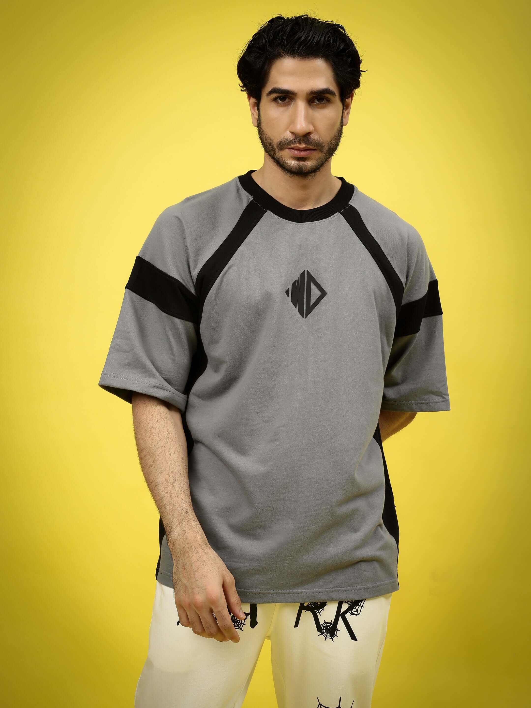Model wearing TURBO OVER-SIZED T-SHIRT SLATE GREY made from premium heavy gauge fabric in front of yellow background.