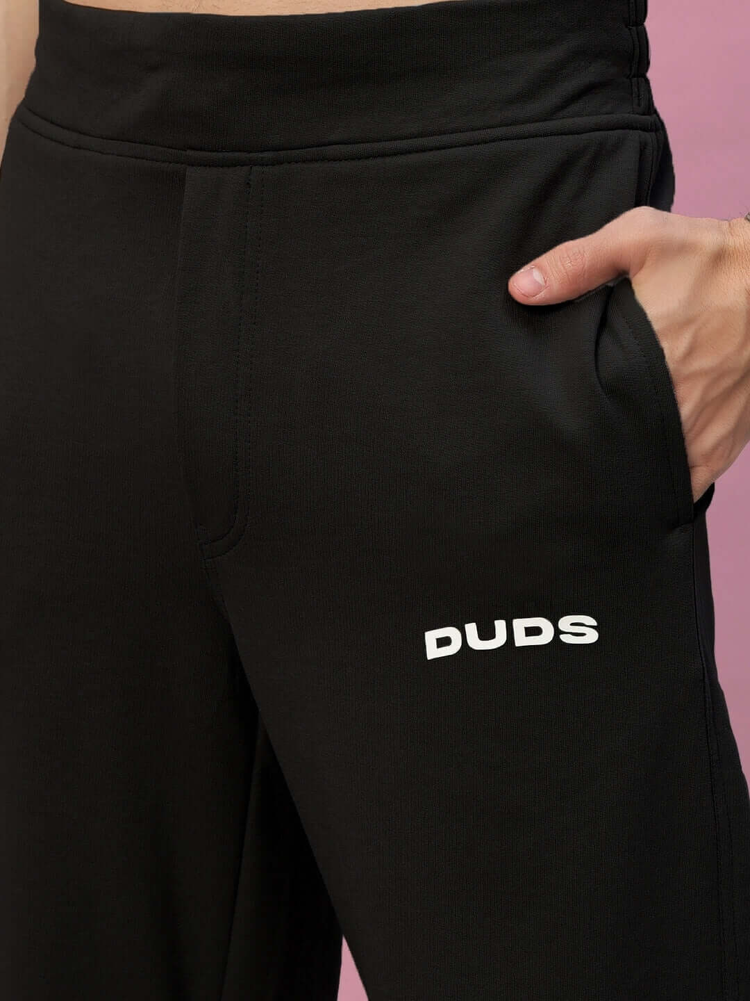Black NEW ERA relaxed fit joggers by DUDS with custom fit and made-to-order options, shown with hand in pocket.
