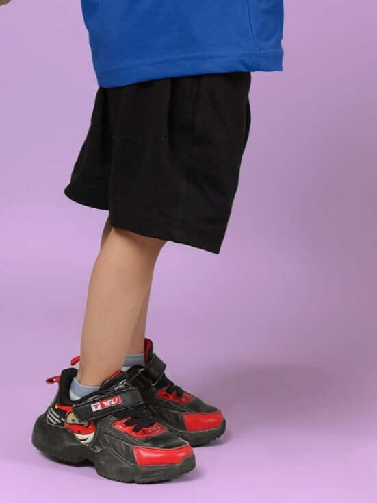 Child wearing Amiga black shorts paired with blue top, showcasing casual kids' clothing by DUDS. Made-to-order quality.
