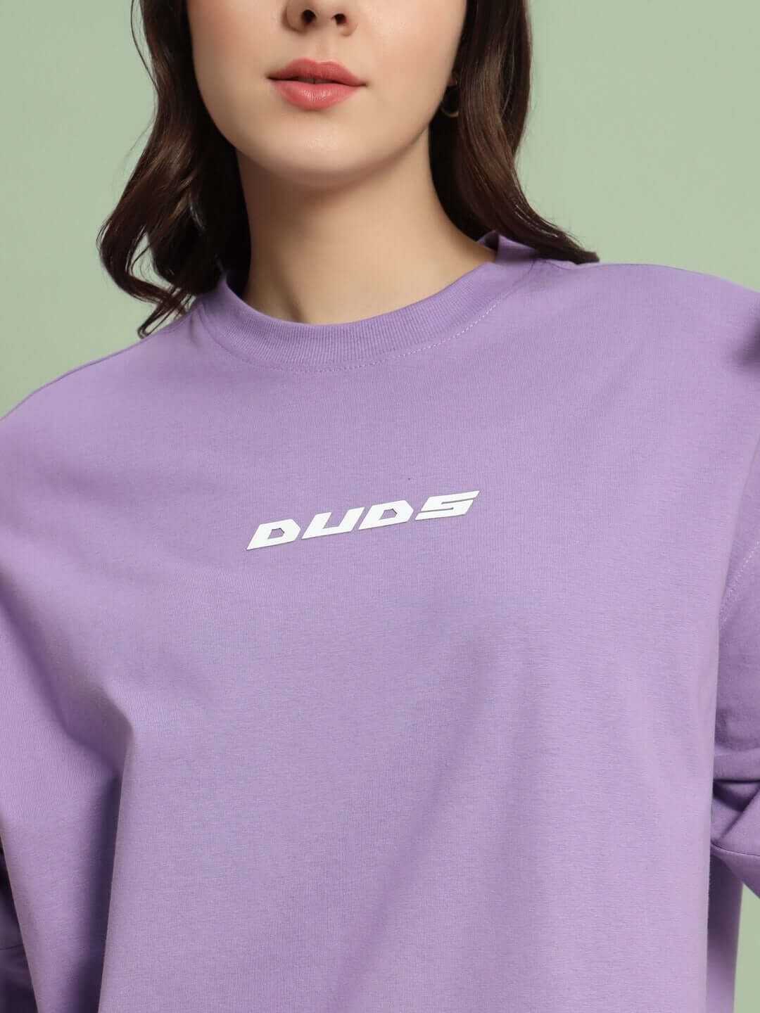 Woman wearing lavender oversized t-shirt with DUDS logo. Custom fit option available for handmade, limited edition apparel.