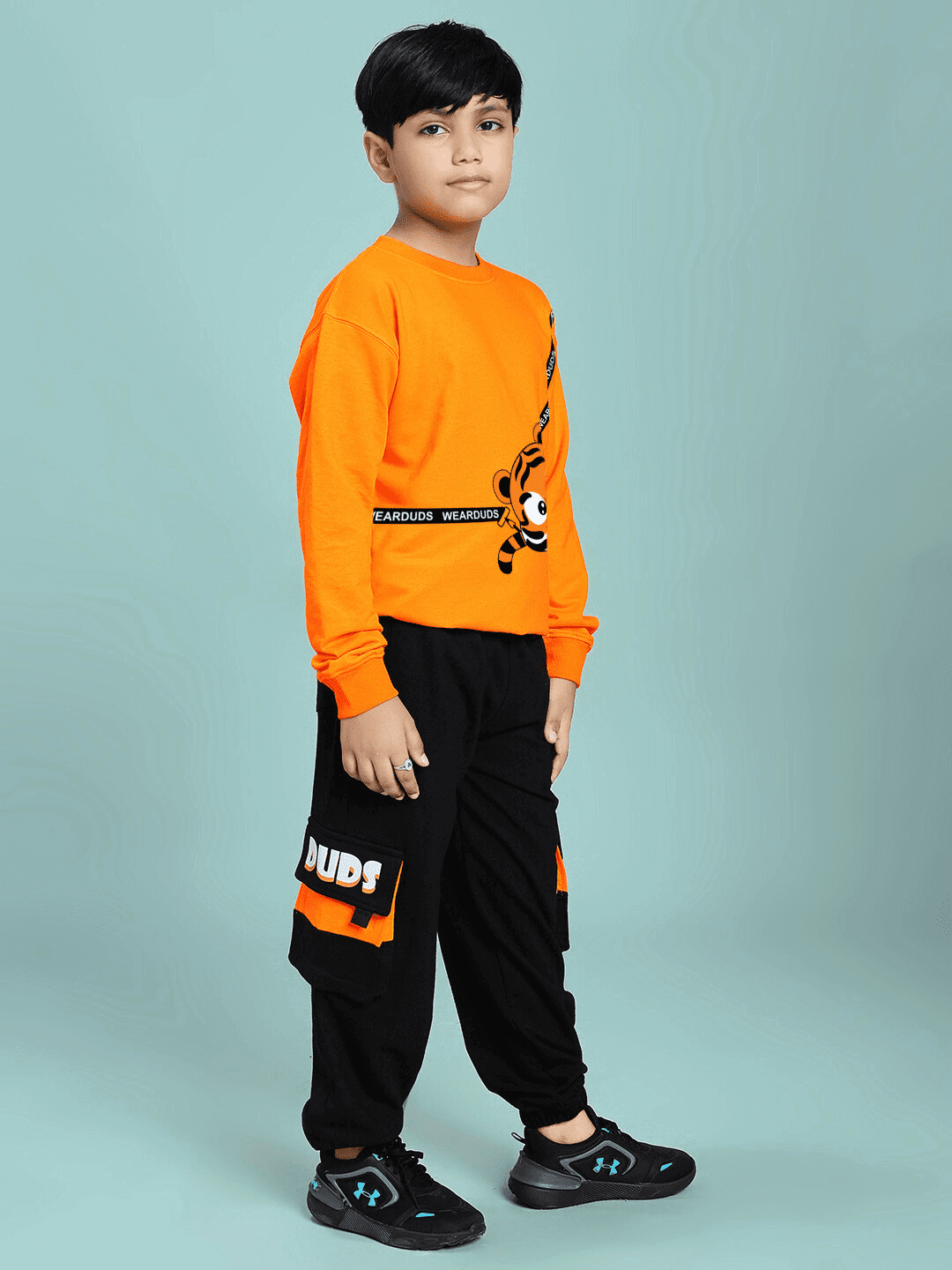 Child wearing TIGON KIDS CO-ORD SET FOR BOYS AND GIRLS ORANGE BLACK, featuring bright orange top and black pants, stylish and comfy.