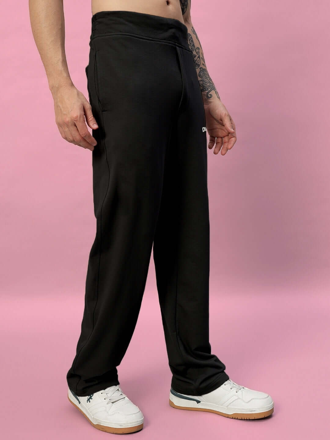 Man wearing New Era Relaxed Fit Joggers in black, showcasing comfortable and stylish design against a pink background.