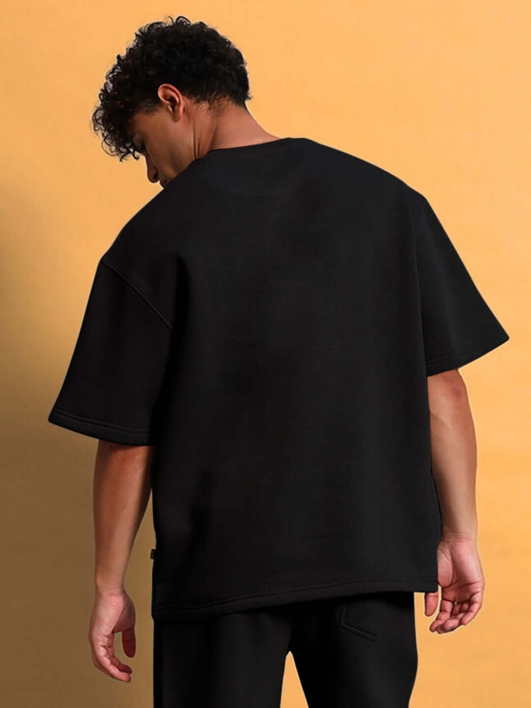 Back view of man wearing SKODA FLEECE OVERSIZED T-SHIRT BLACK, showcasing the oversized fit and plush fleece material.