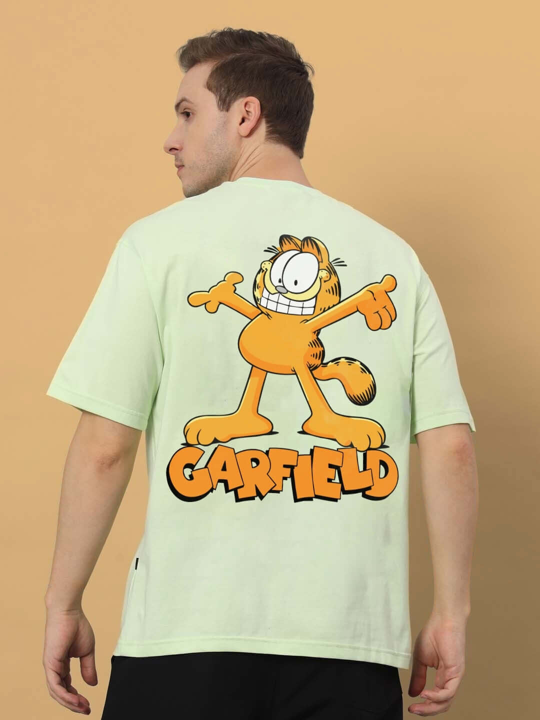 Person wearing GARFIELD OVER-SIZED T-SHIRT CELERY ICE with Garfield cartoon graphic on a light green background.