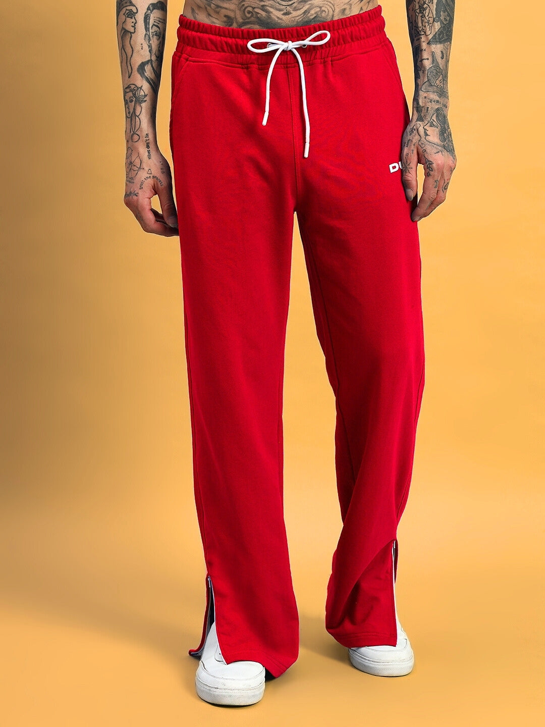 Man wearing Hershey Side Slit Joggers in red with white drawstring, showcased against a mustard background.