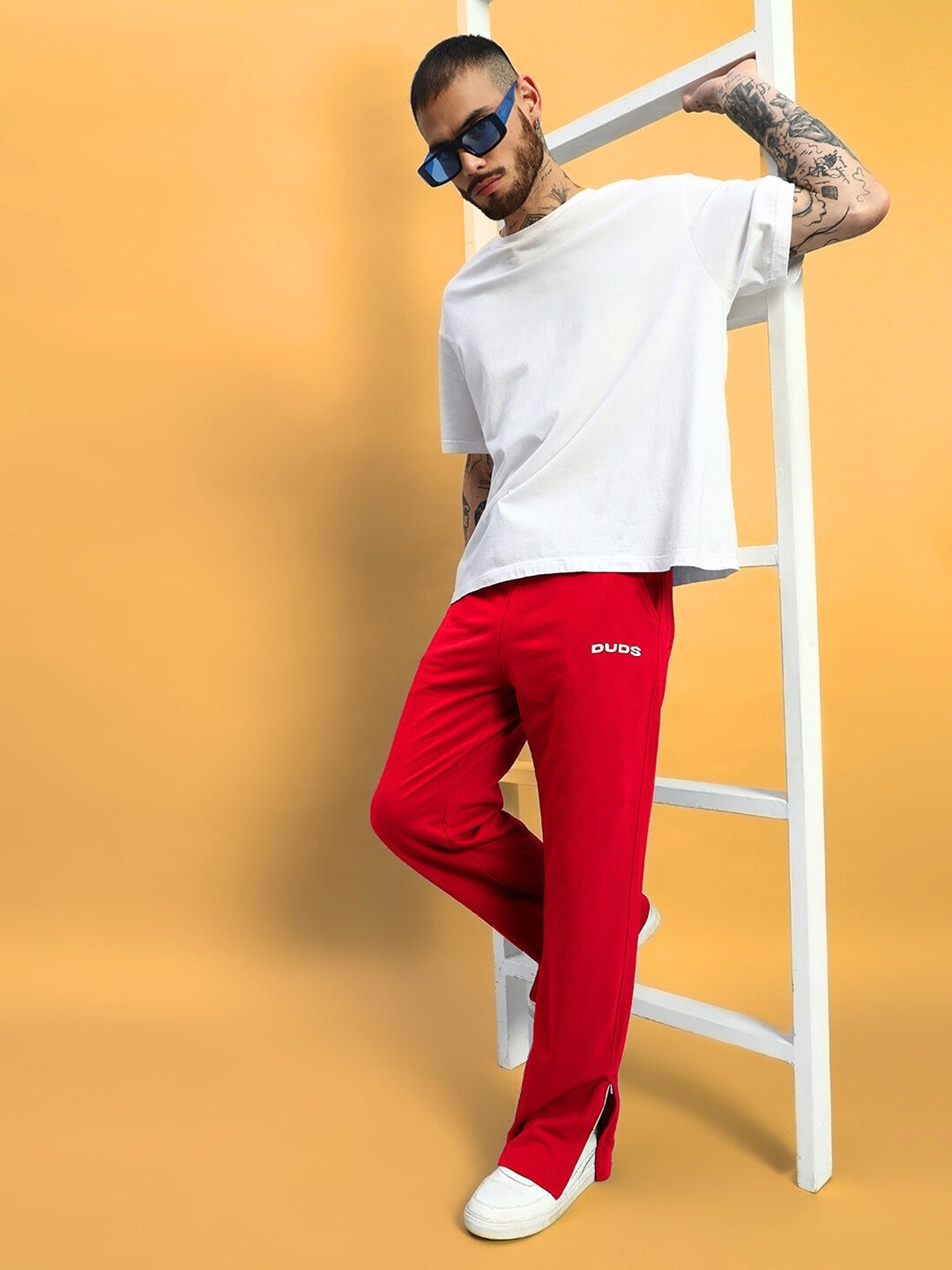 Model wearing HERSHEY SIDE SLIT JOGGERS in red with trendy casual outfit in studio.