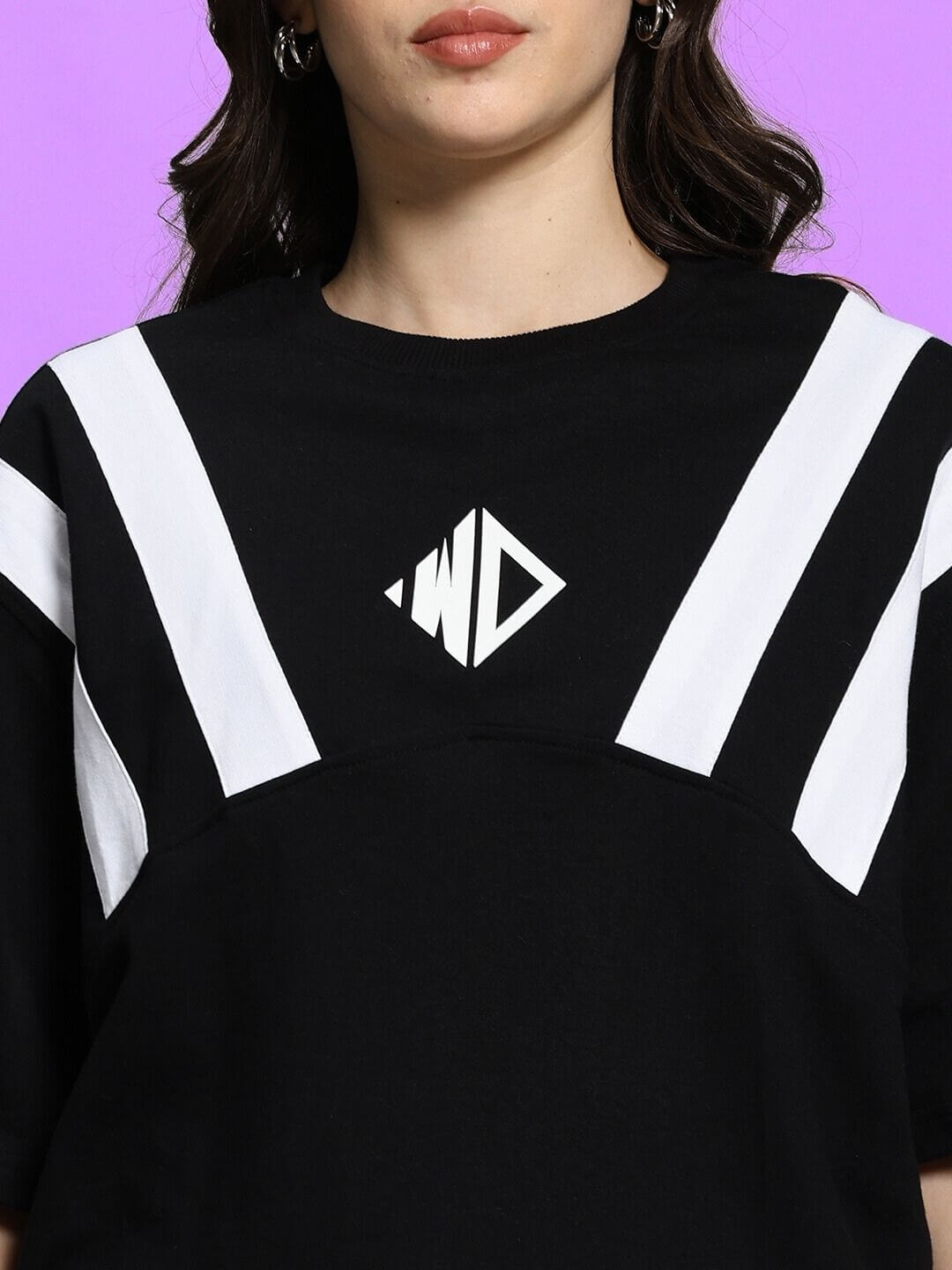 Woman wearing black oversized Allonzo T-shirt, featuring white geometric design, made of premium cotton blend. Ideal for casual style.