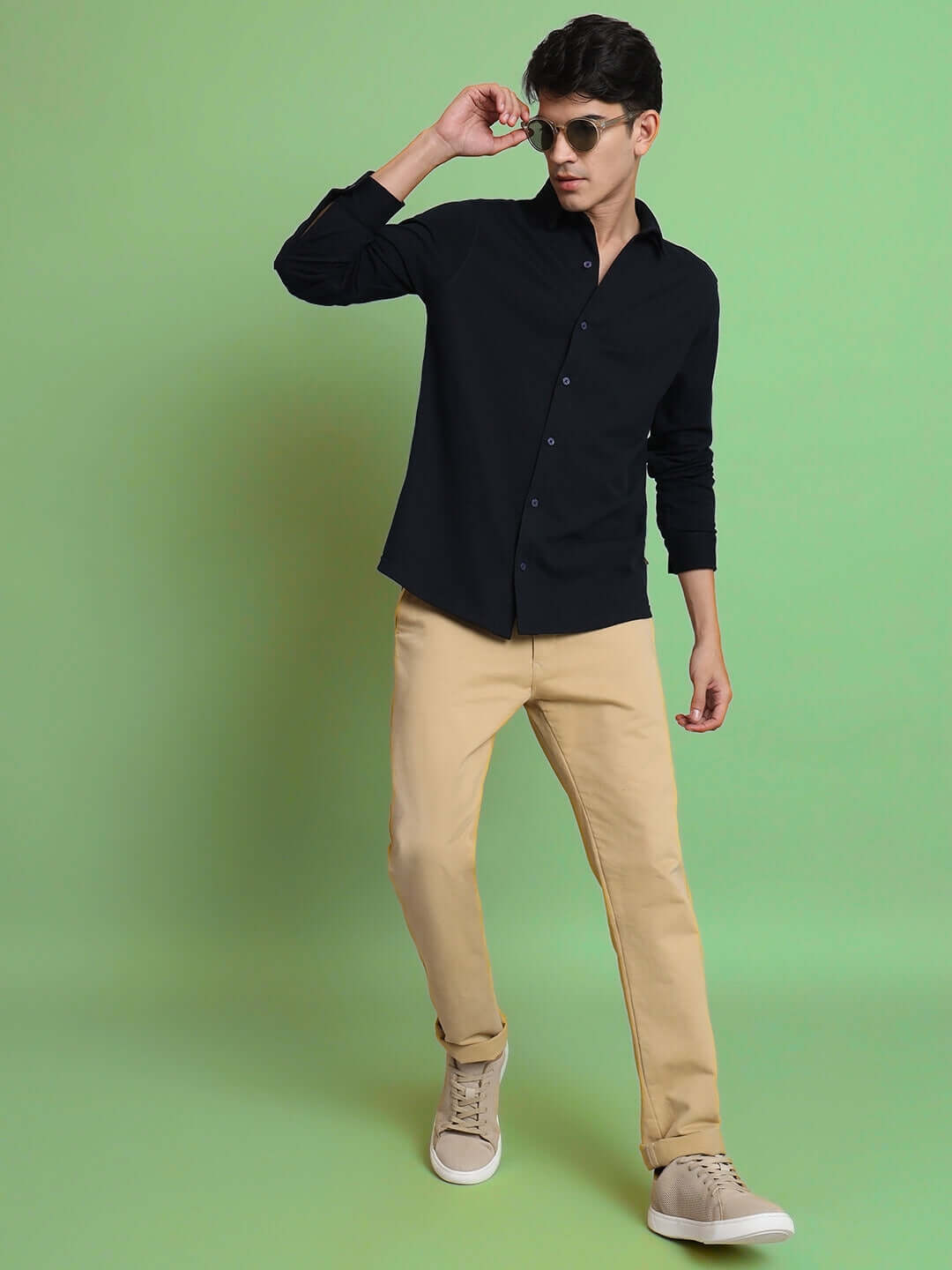 Model wearing a navy blue sporty pique shirt with full sleeves and slim fit, paired with beige trousers, showcasing a stylish and comfortable look.