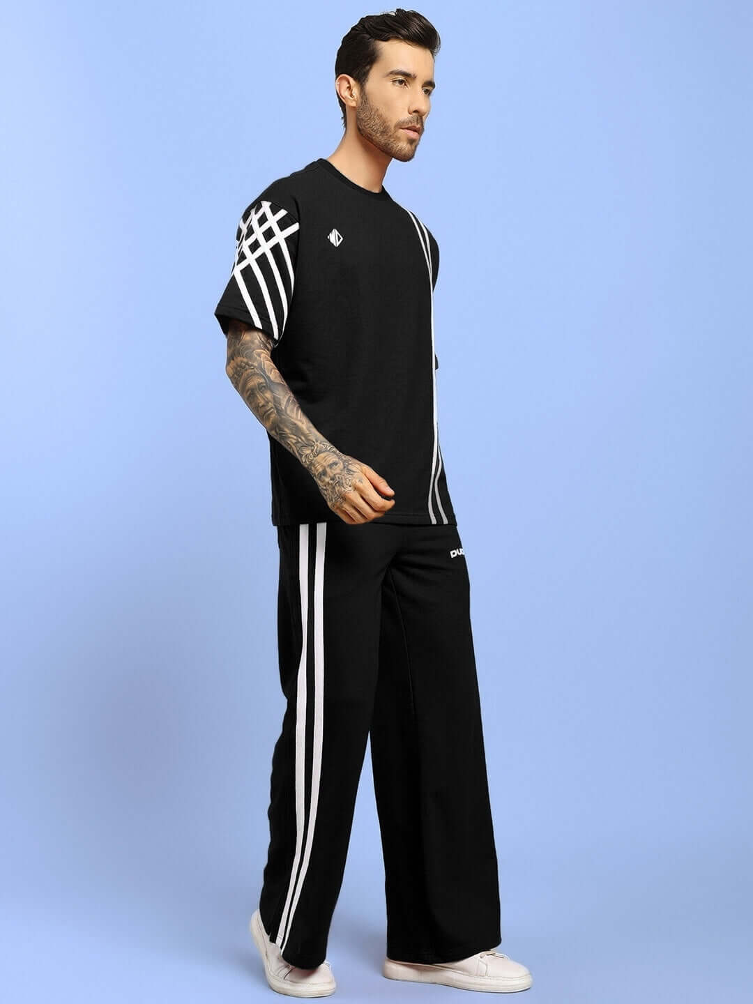 Model wearing UNITED STRIPE CO-ORD SET in black, made from premium cotton fabric. Features stylish white stripes. Perfect for trendy casual wear.