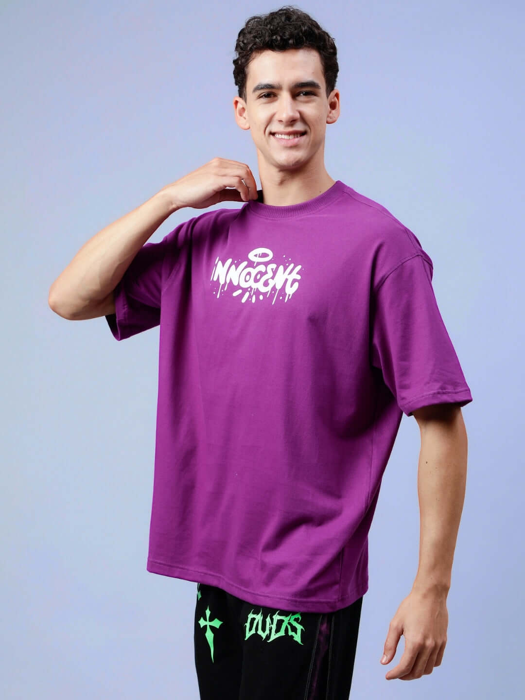 Man wearing INNOCENT OVER-SIZED T-SHIRT PURPLE with bold logo, perfect for casual style.