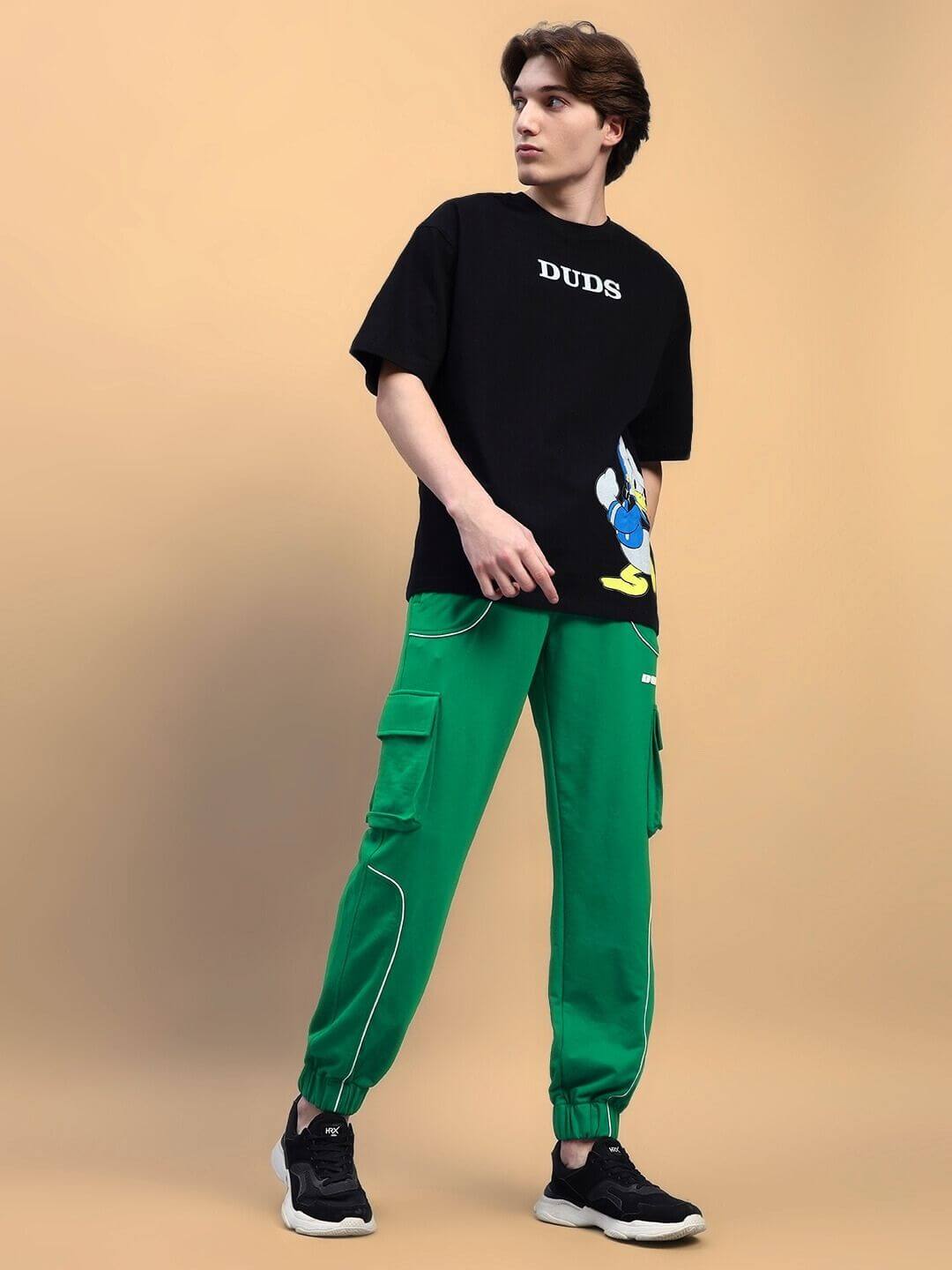 Model wearing Deveno Relaxed-Fit Joggers in green by DUDS, standing with a casual pose, showcasing the stylish joggers with side pockets.