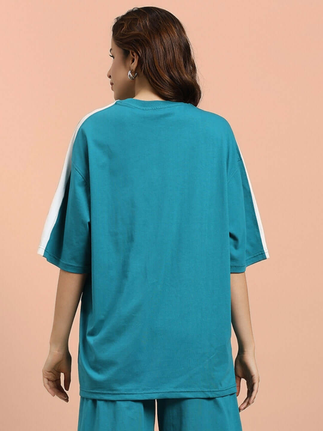 Back view of a woman wearing a teal oversized T-shirt made from premium cotton French terry, ideal for casual wear.