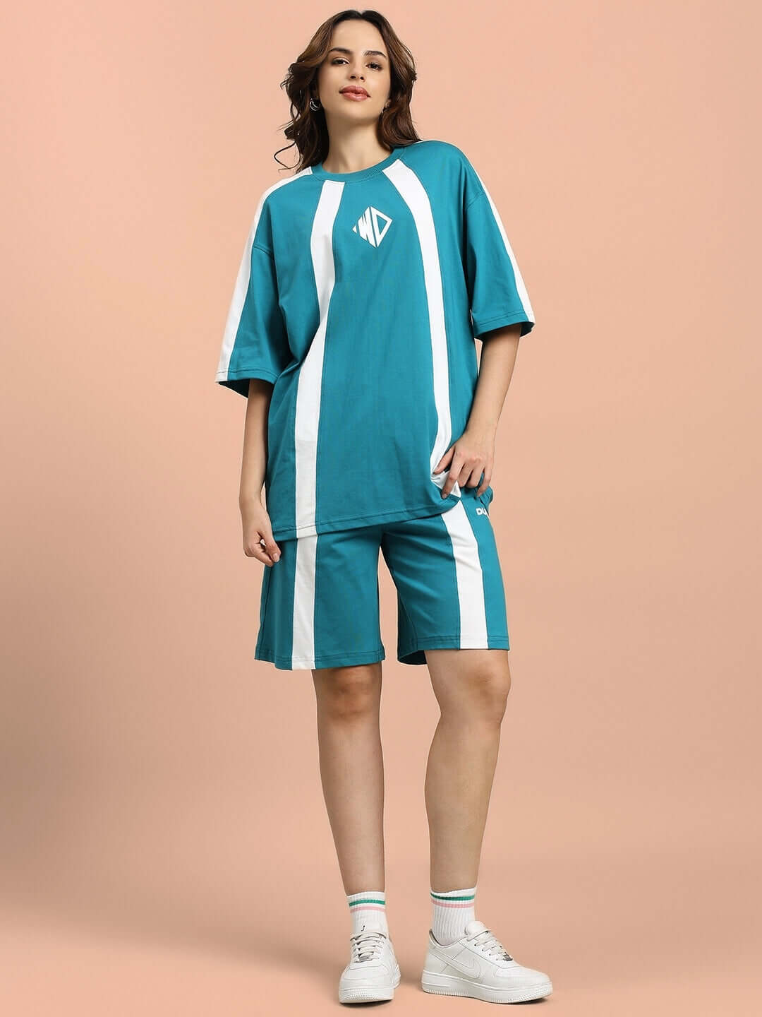 Woman wearing teal WOMEN'S WIDELINE REGULAR FIT SHORTS with matching t-shirt, showcasing casual athletic style.