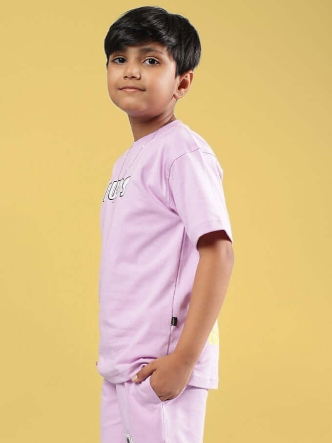 Youth wearing lilac Wolf Pack T-shirt, side view against yellow background.