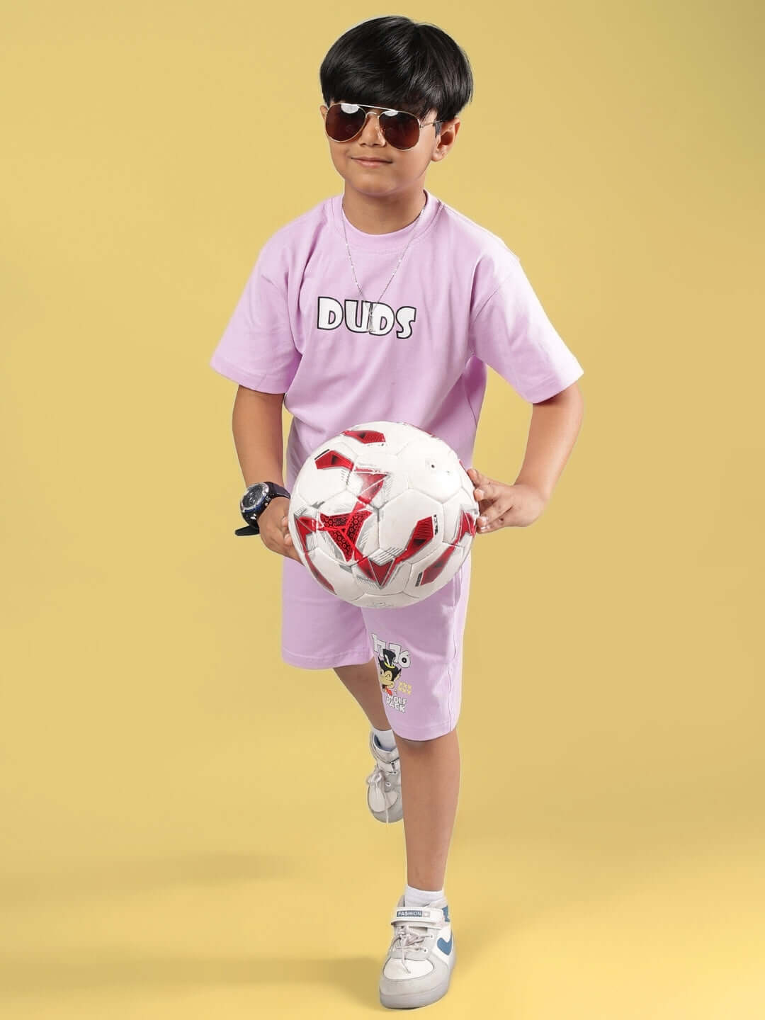 Young boy in lilac DUDS t-shirt playing with a soccer ball, showcasing the Wolf Pack design for boys and girls.