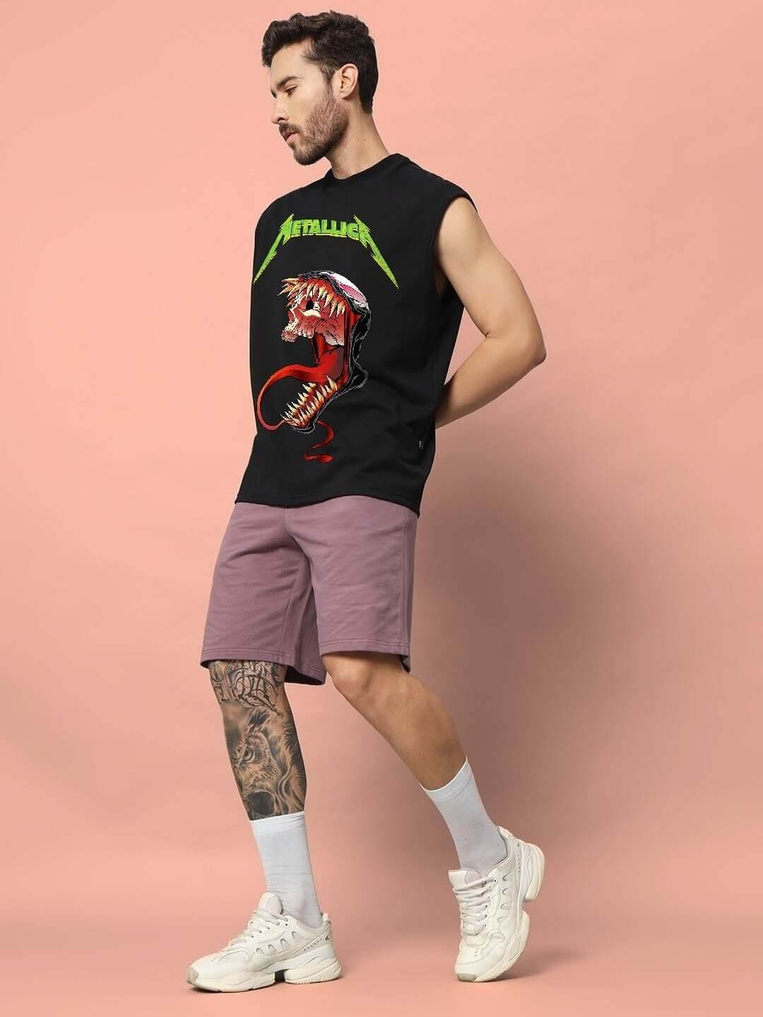 Man wearing a black sleeveless gym t-shirt with graphic design and purple shorts, standing against a peach background.