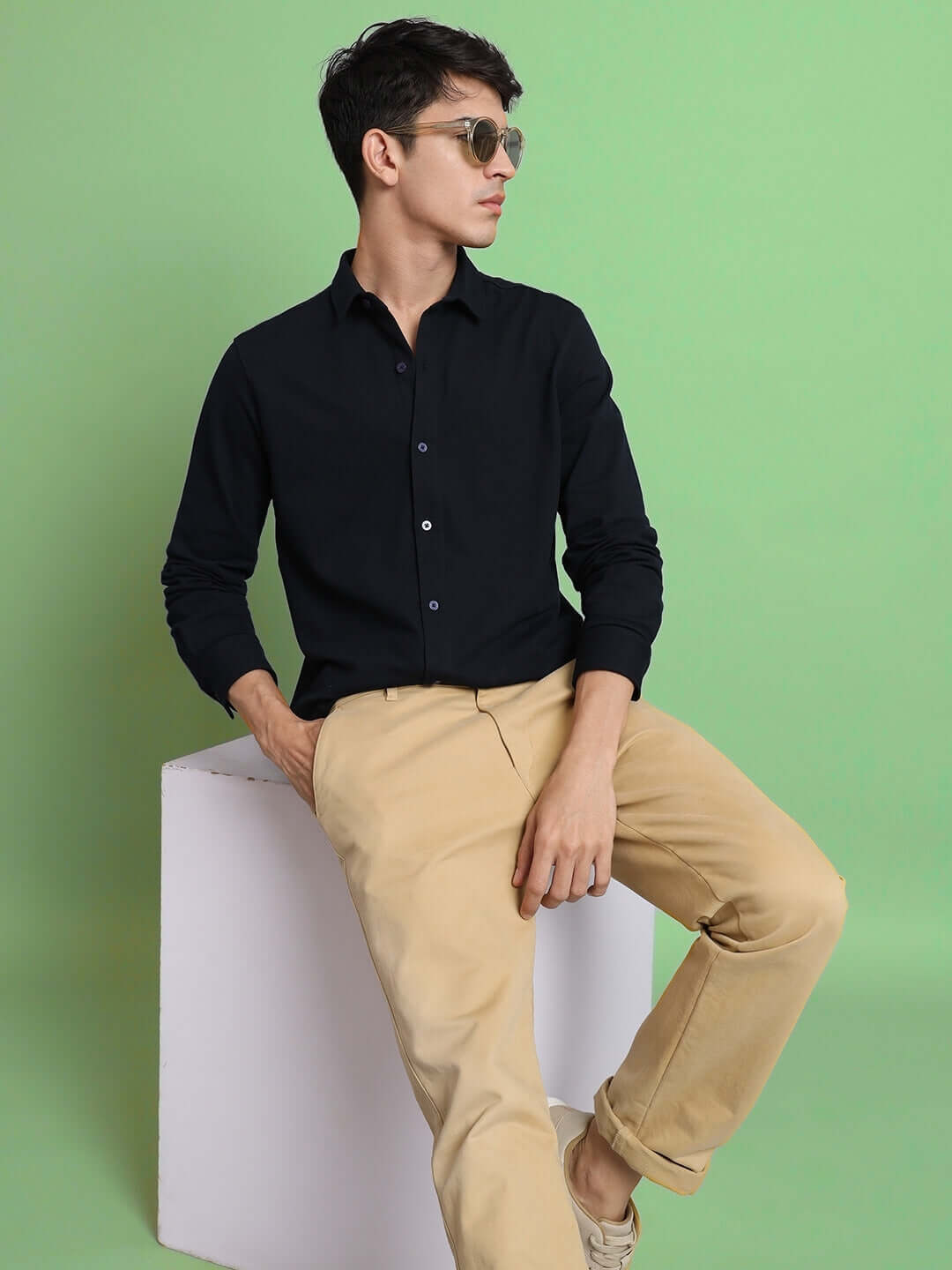 Model wearing Navy Blue Sporty Pique Shirt, full sleeve, slim fit, with khaki pants in a stylish pose on a green background.