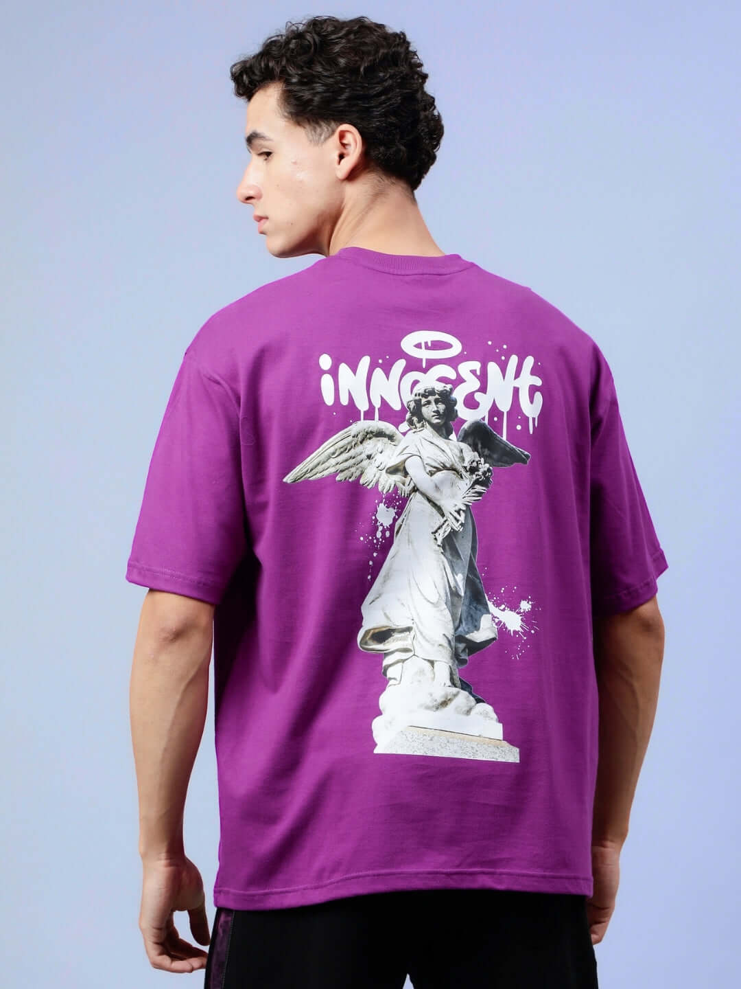 Man wearing INNOCENT OVER-SIZED T-SHIRT PURPLE with angel graphic on back.