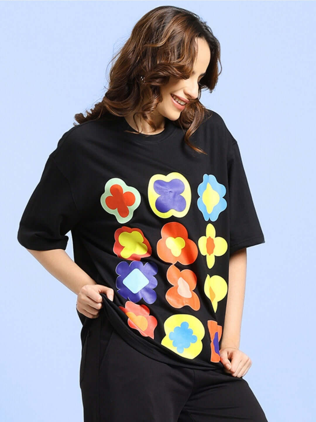 Woman wearing black oversized Hollister T-shirt with colorful floral design, made from premium cotton blend, perfect for casual style.