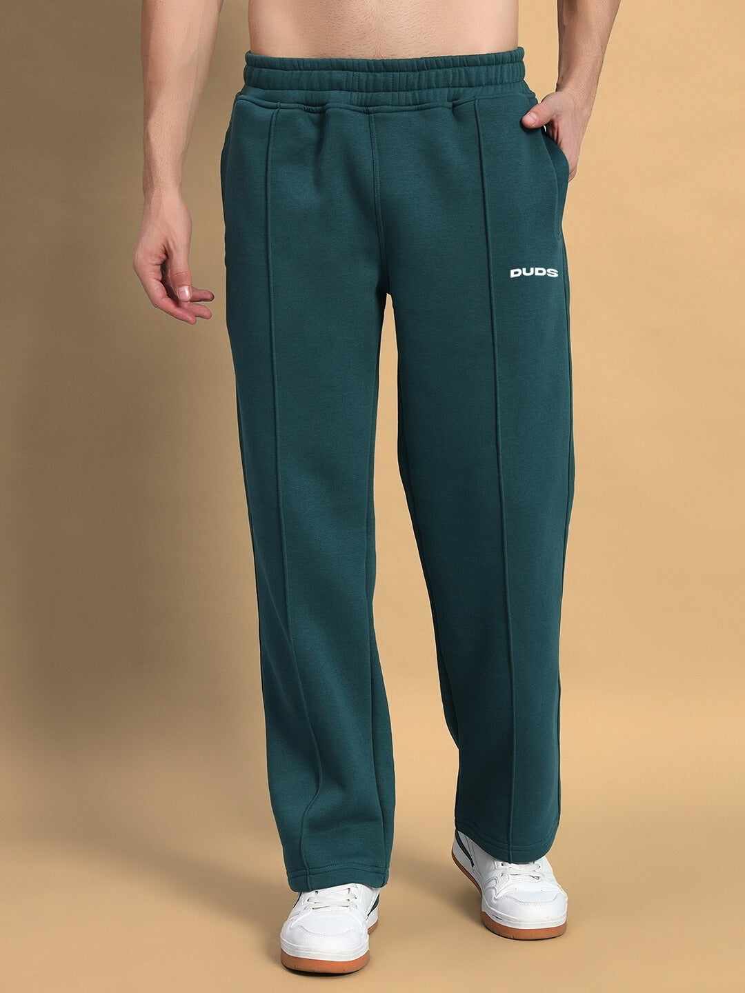 Teal green shaggy fleece jogger pants with elastic waistband and side logo, worn with white sneakers.