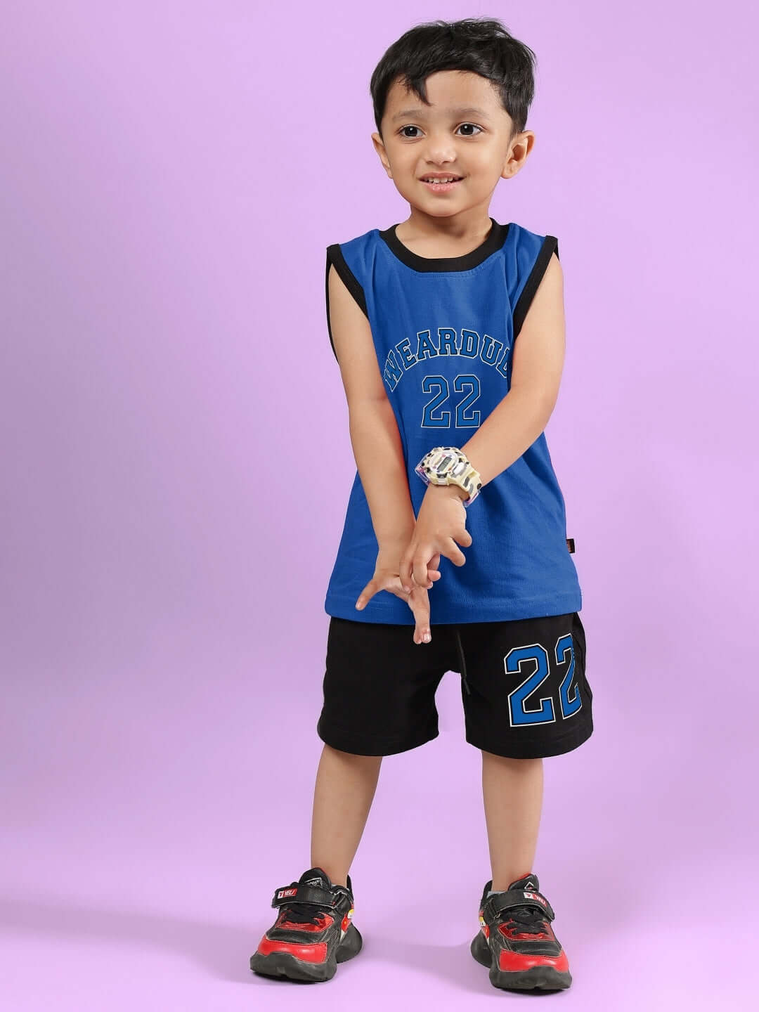 Child wearing AMIGA black and blue shorts with matching top, standing on a purple background, showcasing DUDS custom-fit nautical style.