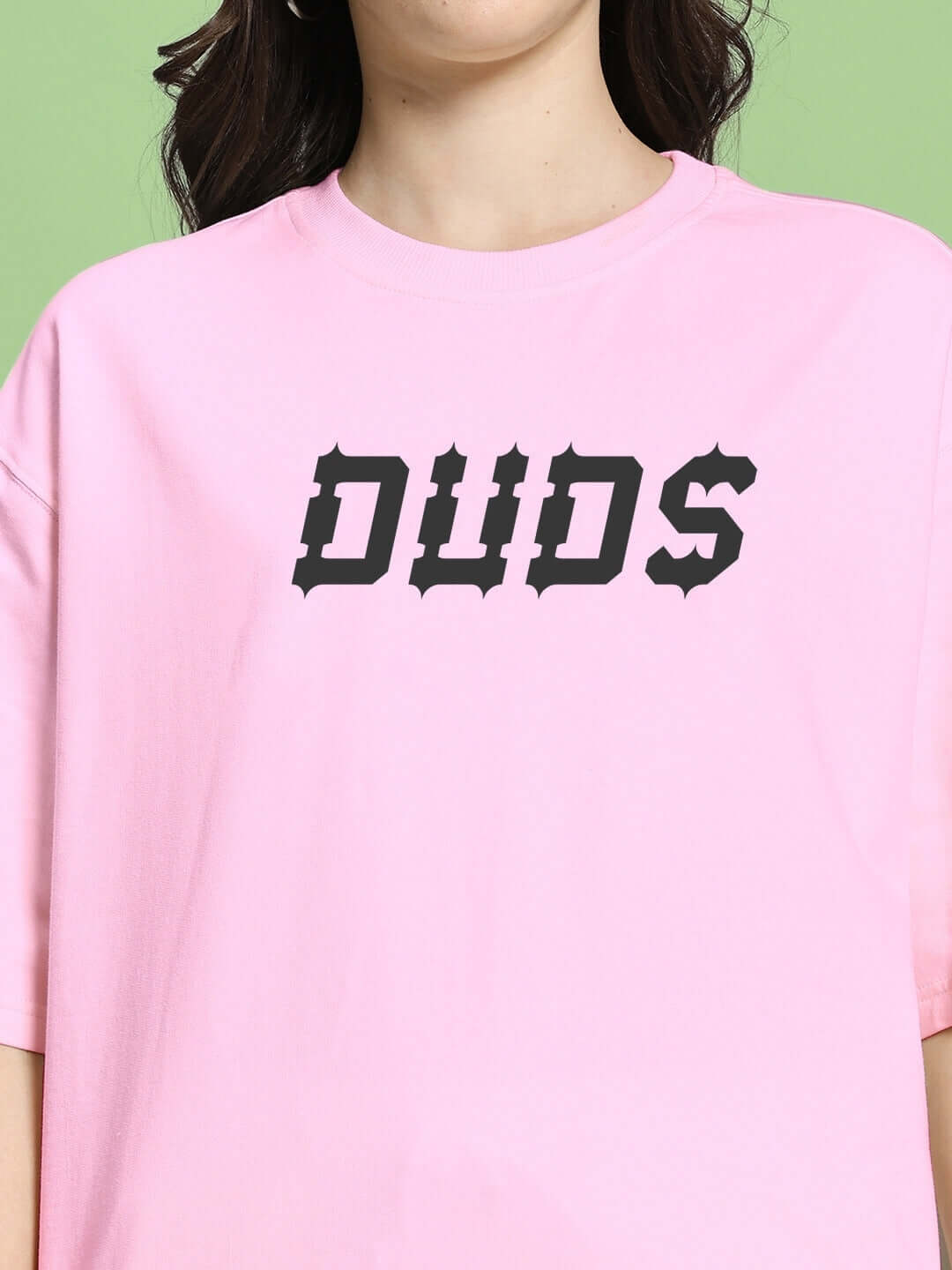 Woman wearing pink oversized T-shirt with 'DUDS' text print, made from premium cotton French terry fabric, fashion wear from Color By Colours.