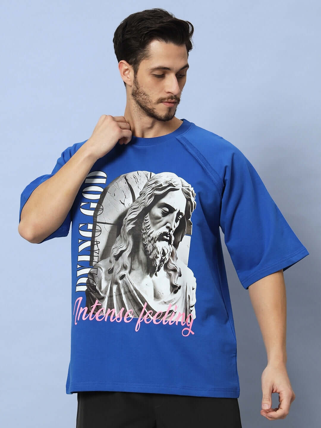Model wearing REGLAN DYING GOD OVER-SIZED T-SHIRT ROYAL BLUE, featuring a bold design with a statue graphic and 'Intense Feeling' text.