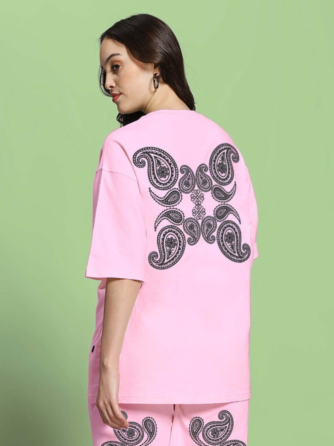 Model wearing women's oversized pink t-shirt with paisley print, made from premium cotton-elastane fabric. Country of origin: India.