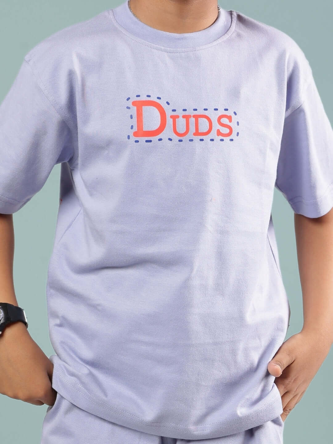 Child wearing a lavender SAMMY T-shirt for boys and girls, featuring the DUDS logo.