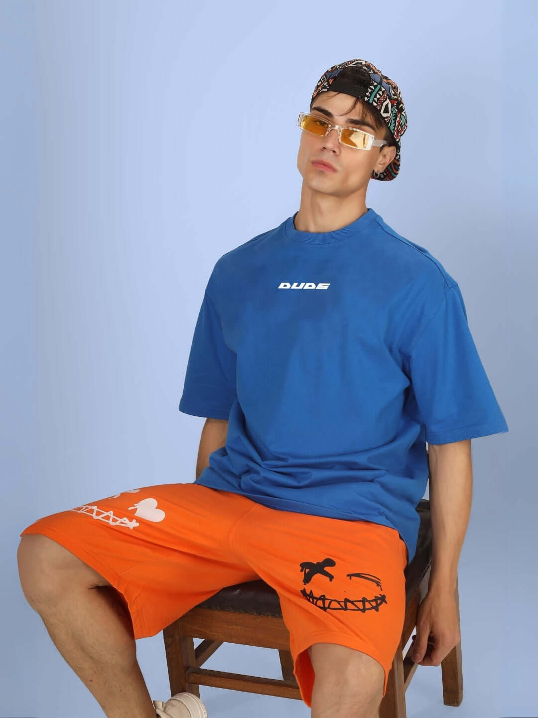 Model wearing DUDS VAN OVER-SIZED T-SHIRT ROYAL BLUE with orange shorts, showcasing customizable fit option for unique style.