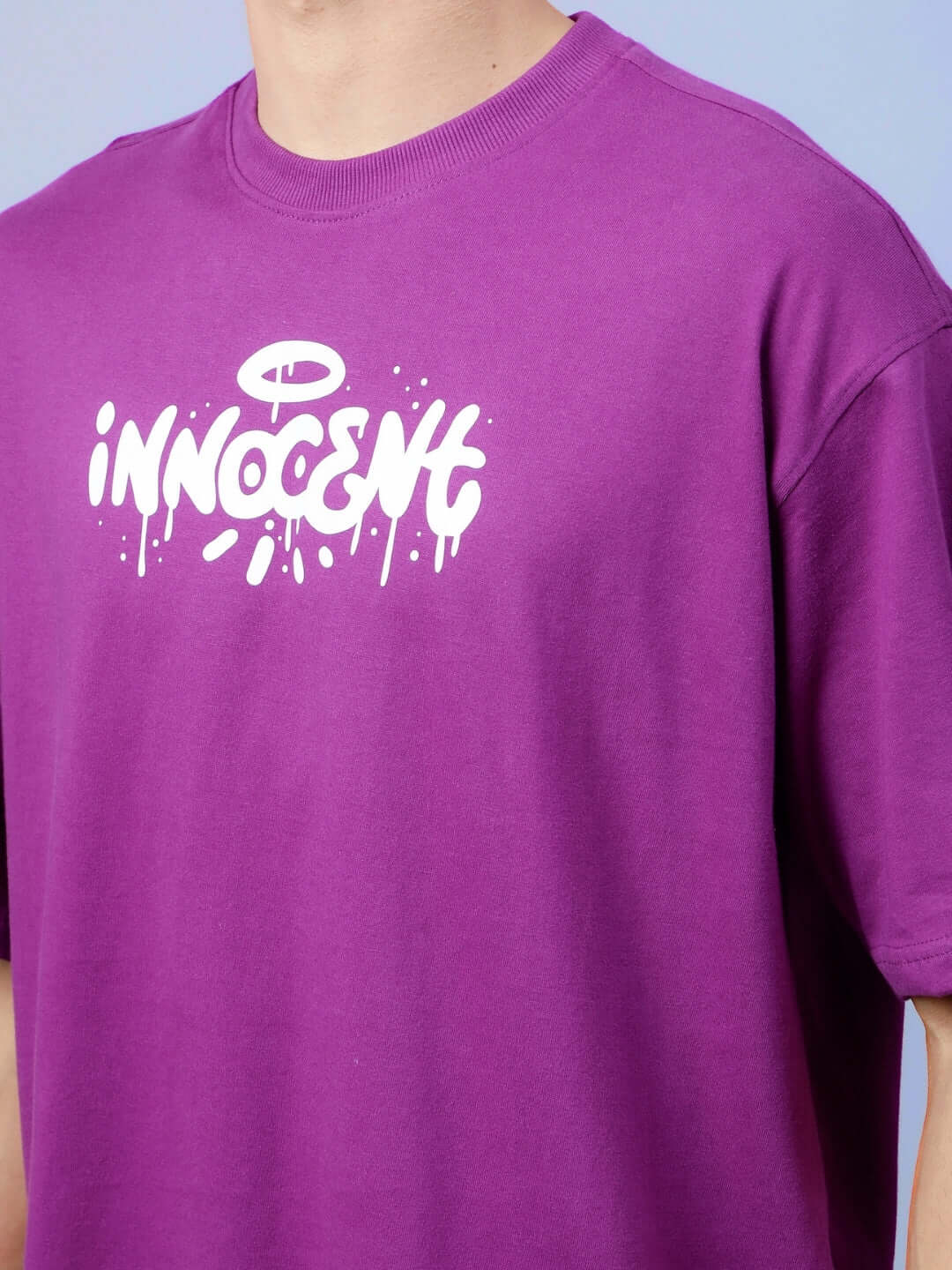 Man wearing INNOCENT OVER-SIZED T-SHIRT PURPLE with white print on front.