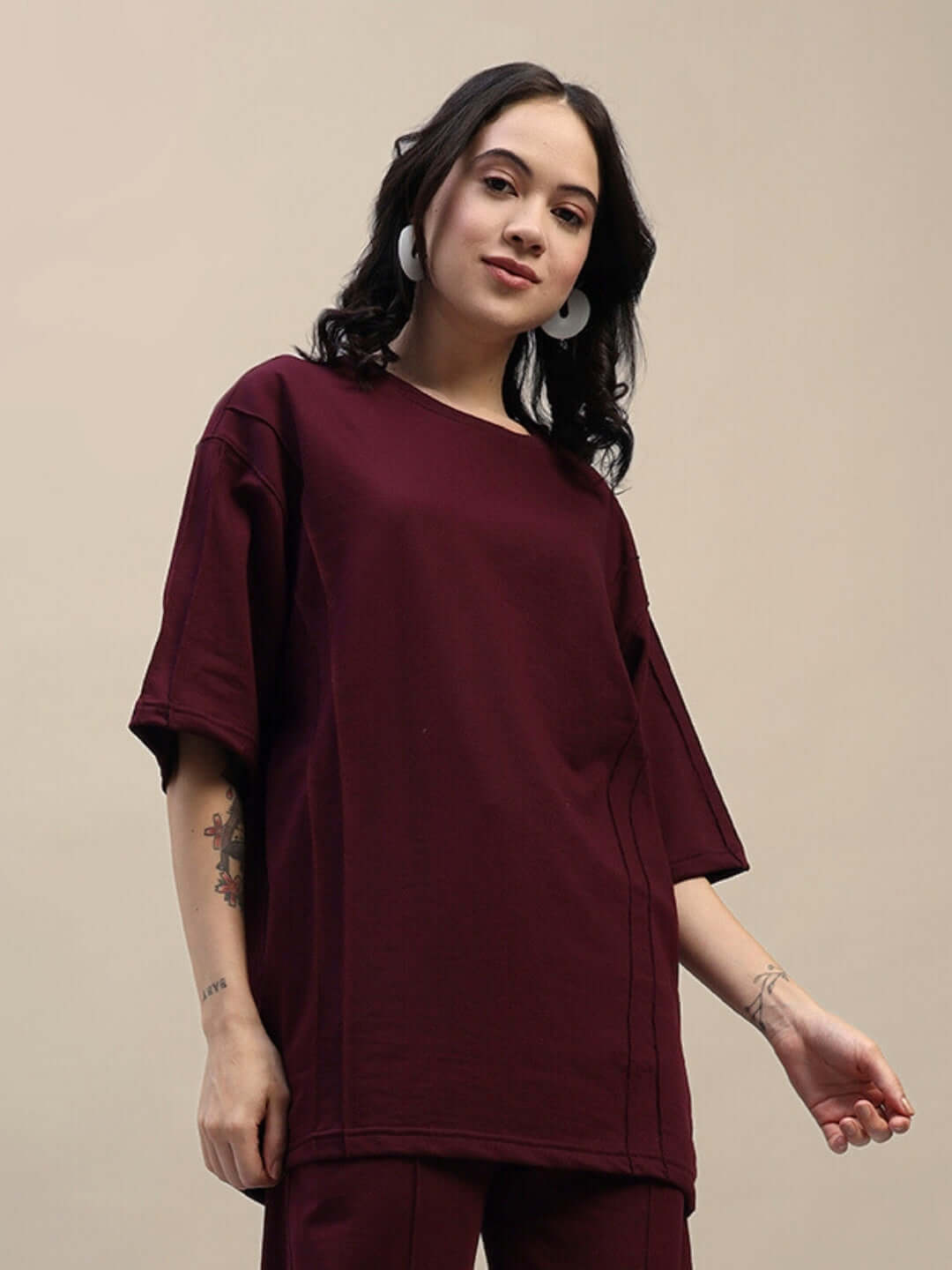 Model wearing women's oversized maroon T-shirt made of premium cotton blend, showcasing relaxed fit and comfortable style.